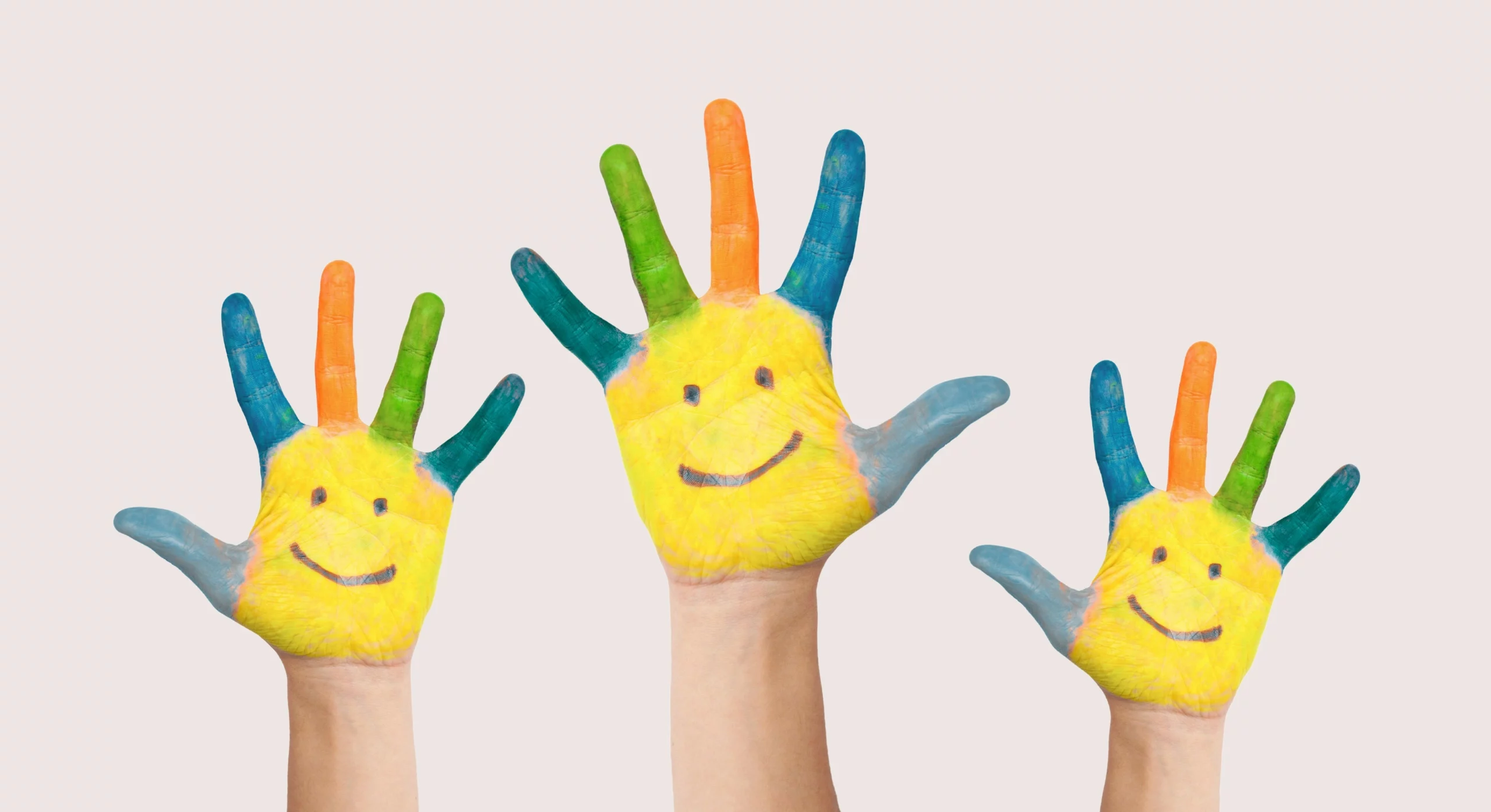 Three children's hands painted with yellow smiley faces and colorful fingers, representing neurodiversity and autism awareness.